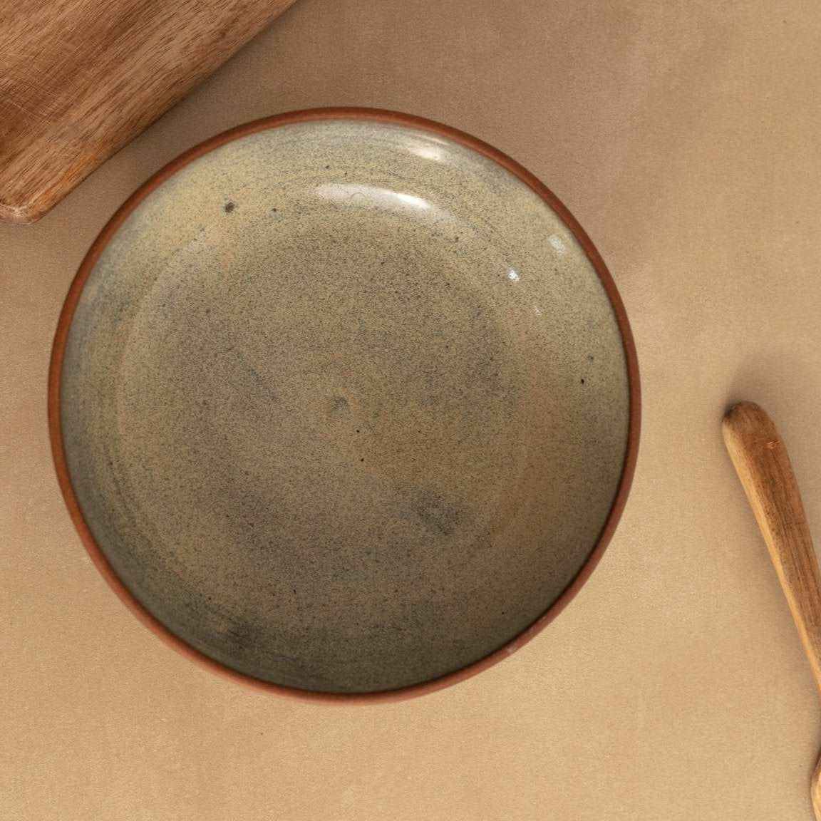 Mottled green meal bowl placed on a rustic dining table.
