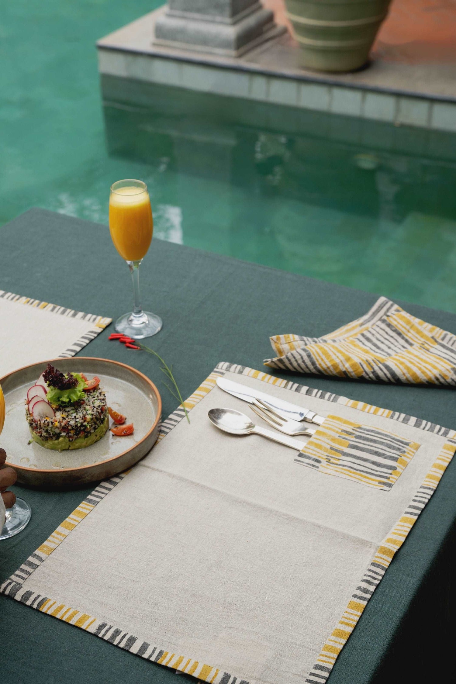 Dining table styled with olive linen tablecloth and modern cutlery.