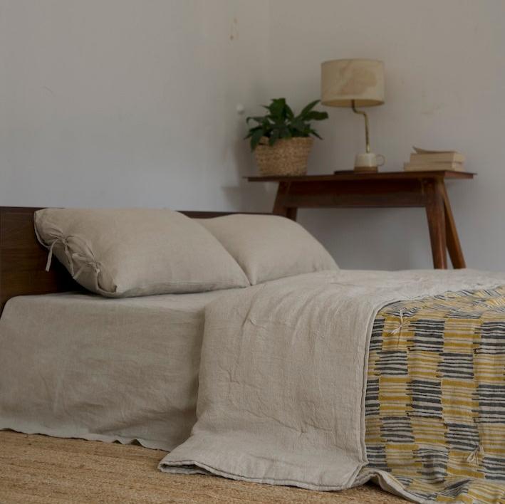 Ochrewood quilt draped on a bed with a neutral linen bedsheet for a minimalist aesthetic