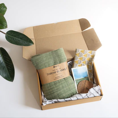 A gift hamper of linen sage green throw and earthy undyed linen hand block printed cushion