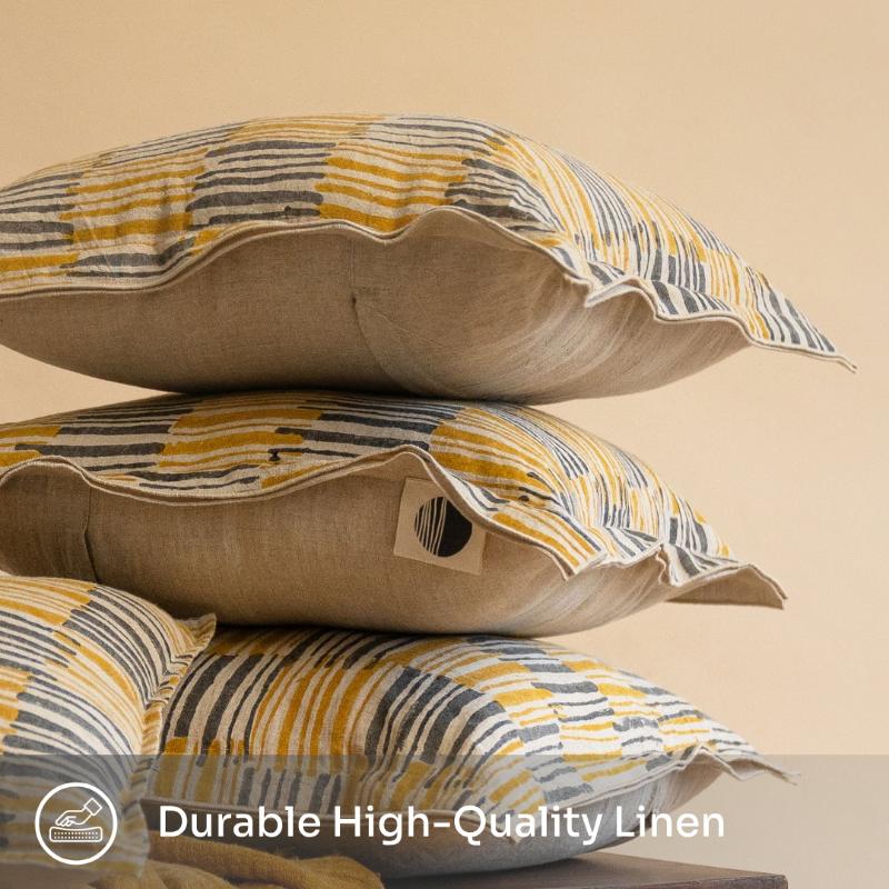 Pair of Ochrewood hand block printed linen cushion covers in mustard ochre, arranged on a stack to enhance the bedroom&