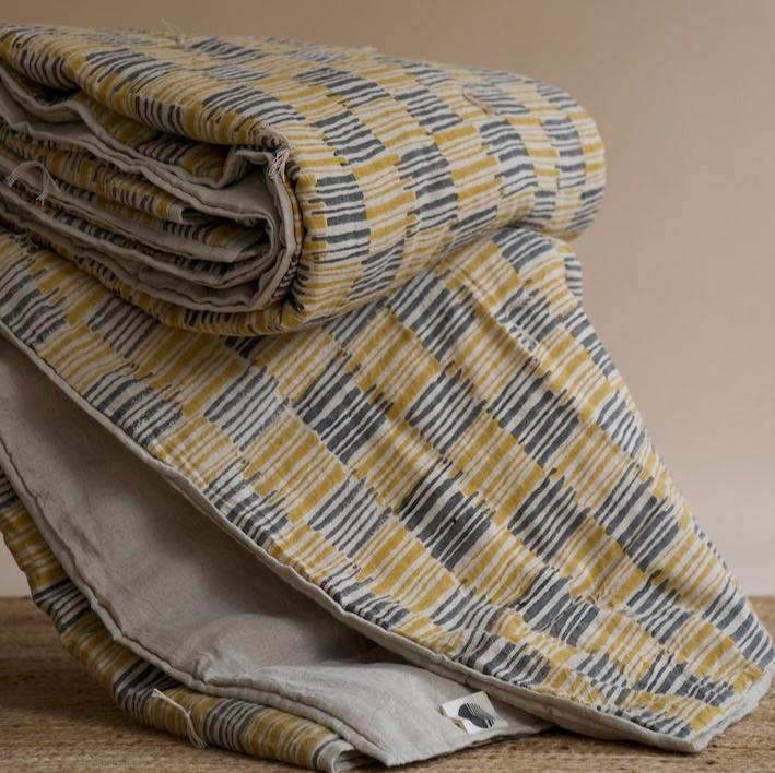 Ochrewood quilt loosely stacked, showcasing its soft texture and earthy tones