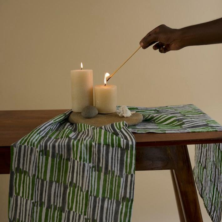 Flat lay of a pure linen table runner in kale green paired with natural elements and romantic candles