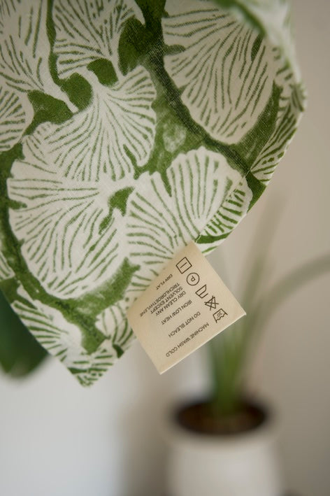 Close-up of Morel napkin showcasing its kale green hue, hand-stitched detailing, and natural linen texture.