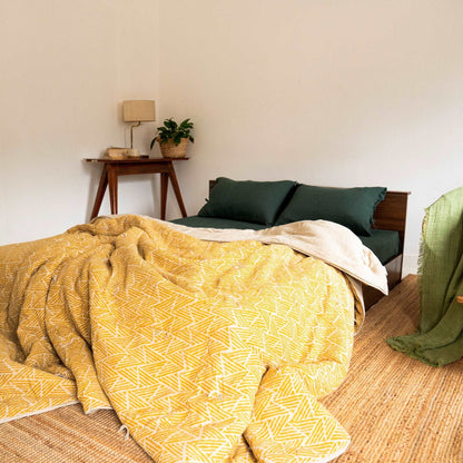 Unmade bed with Amberleaf quilt; cozy and inviting feel