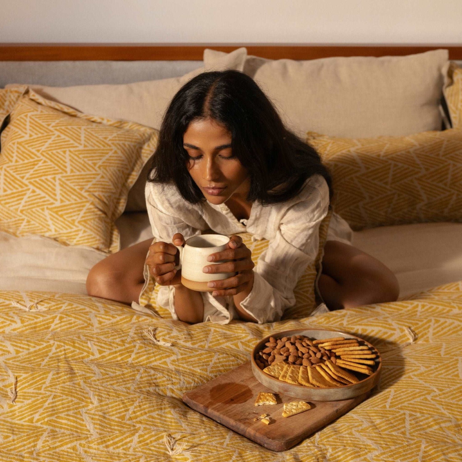 Model enjoying snacks on bed with Amberleaf quilt