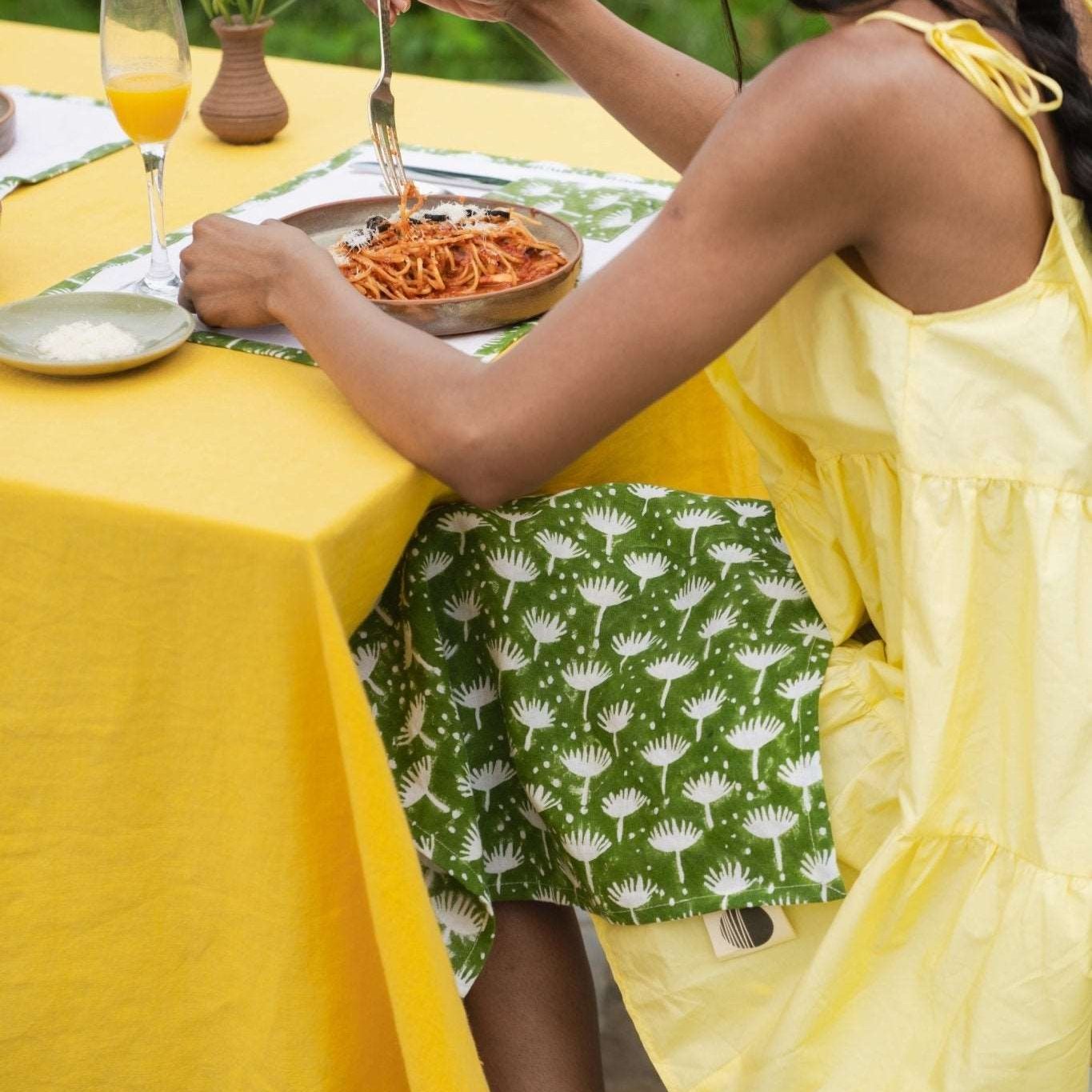 Woman enjoying her dinner alone with Dahlia napkin styled elegantly on the table.