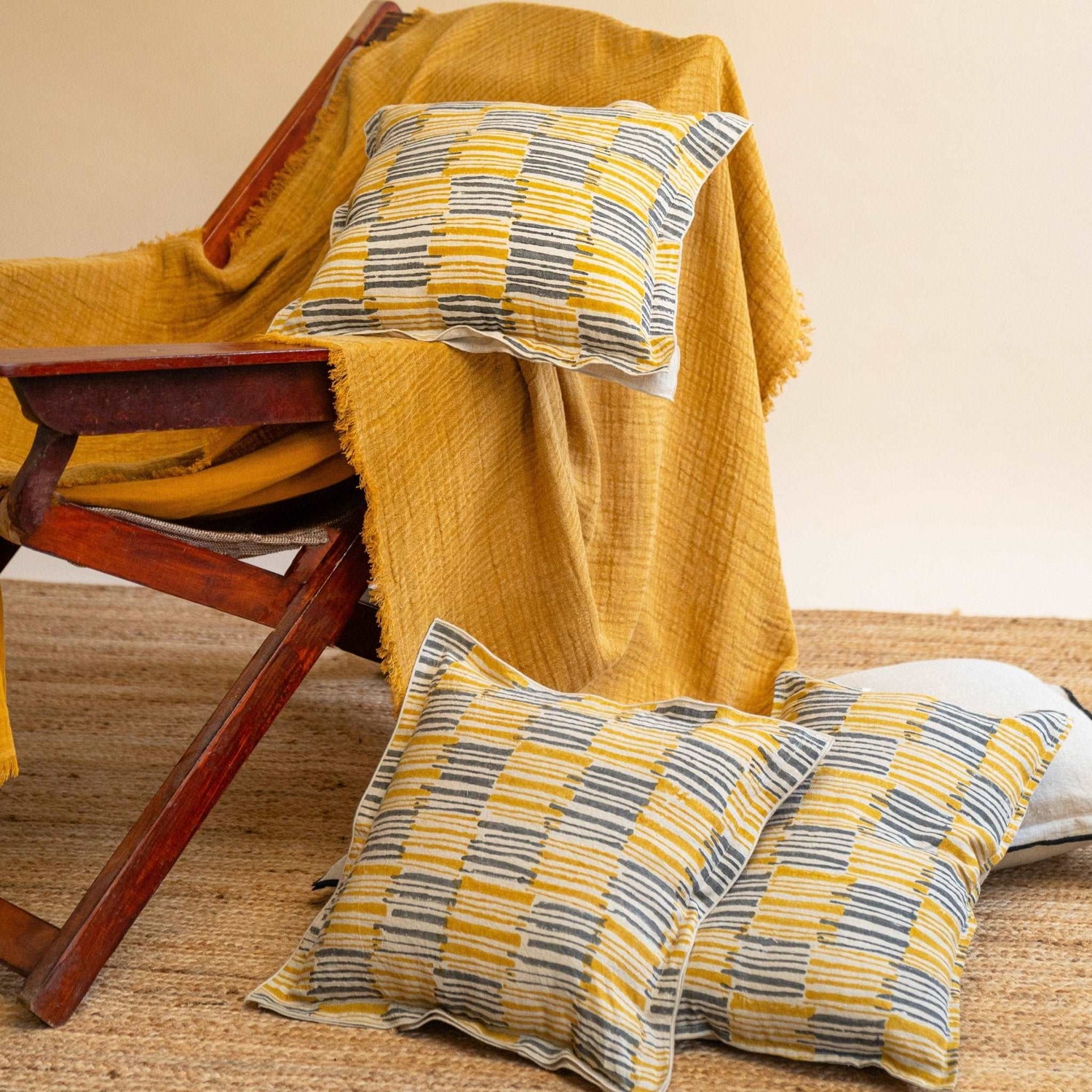 Textured linen and cotton slub throw in Mustard Ochre laid across a vintage chair featuring ochrewood cushions by Terra