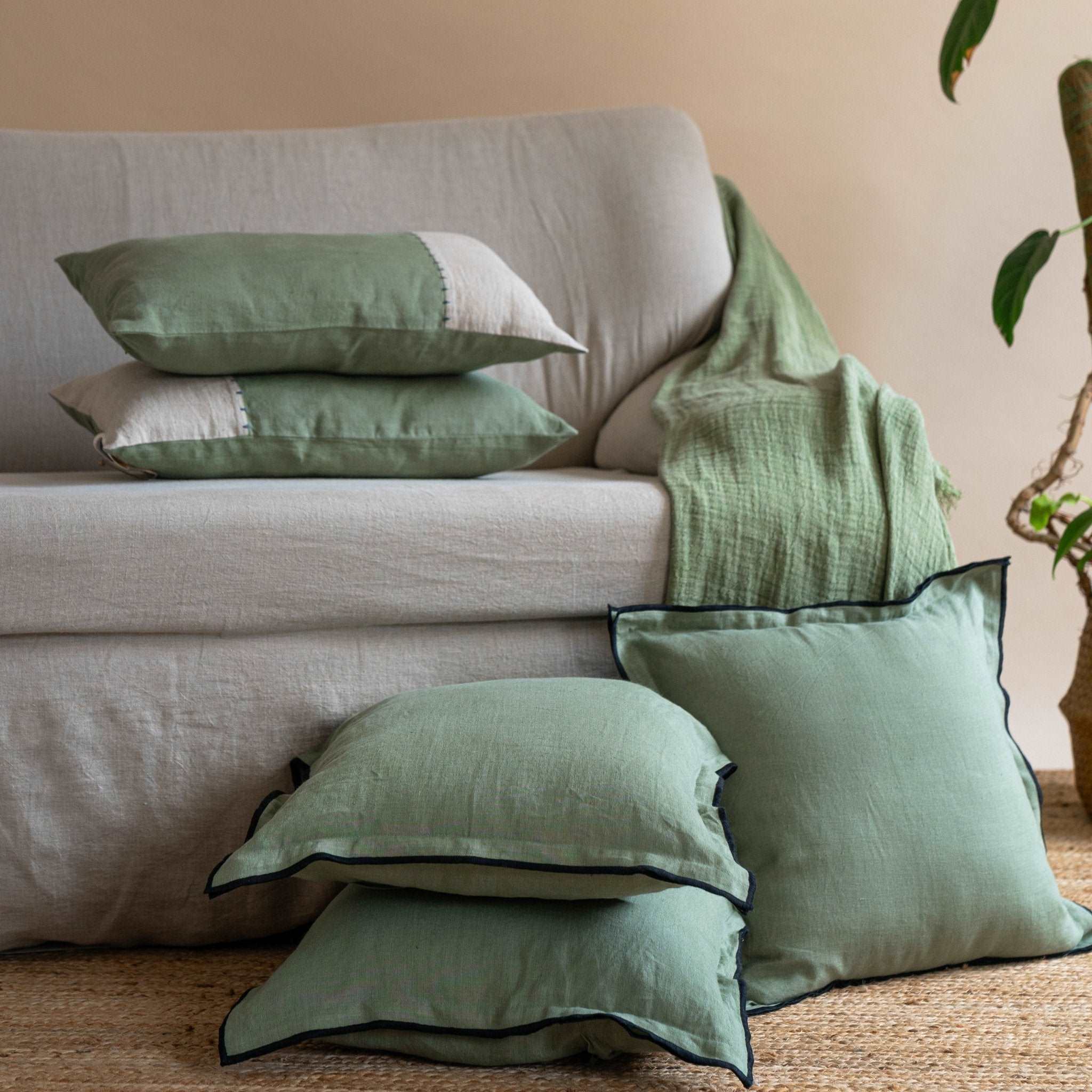 Pair of half olive green and half sand beige linen cushion covers arranged on a bed, enhancing the room&