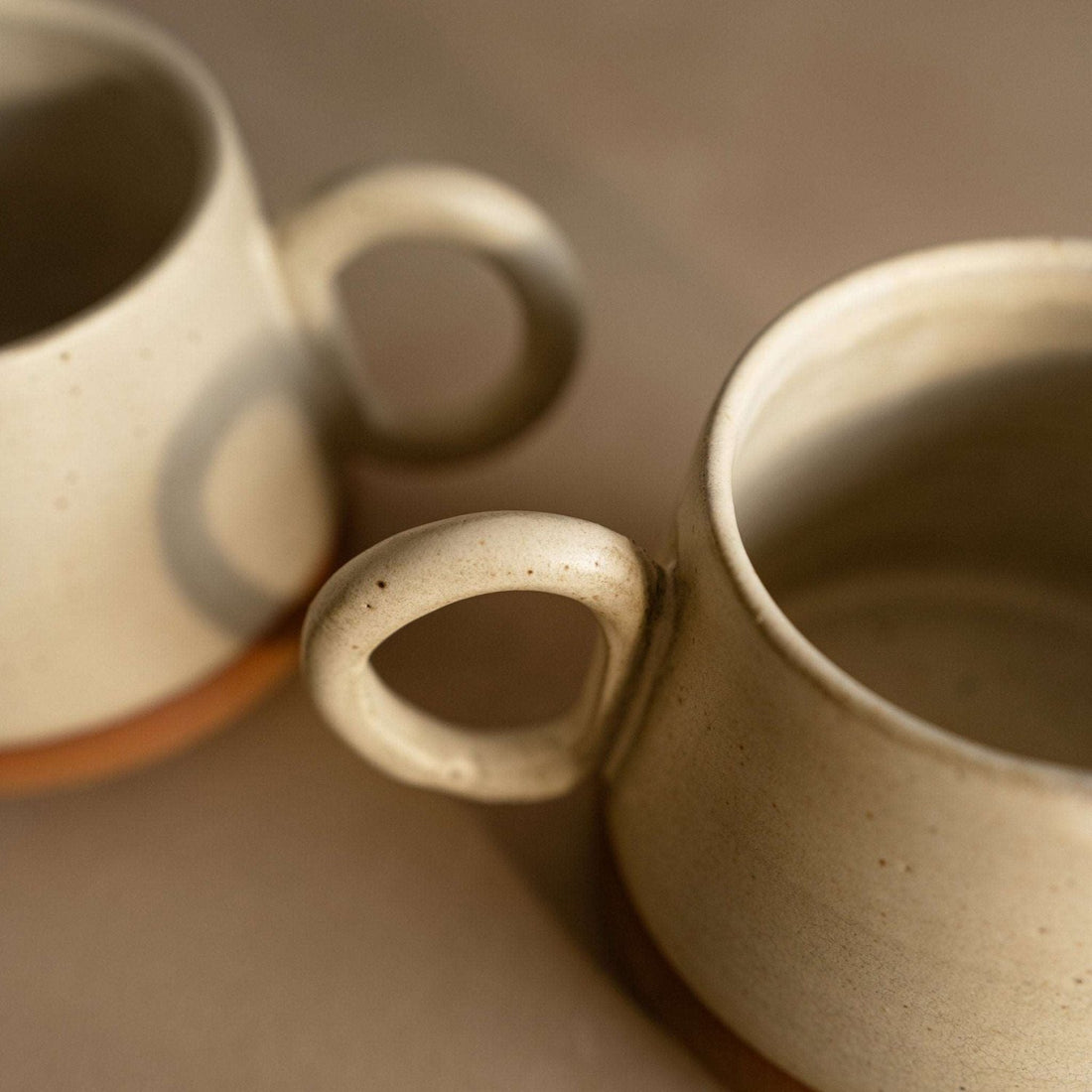 Close-up of a conical coffee mug showcasing its floating cream glaze finish.