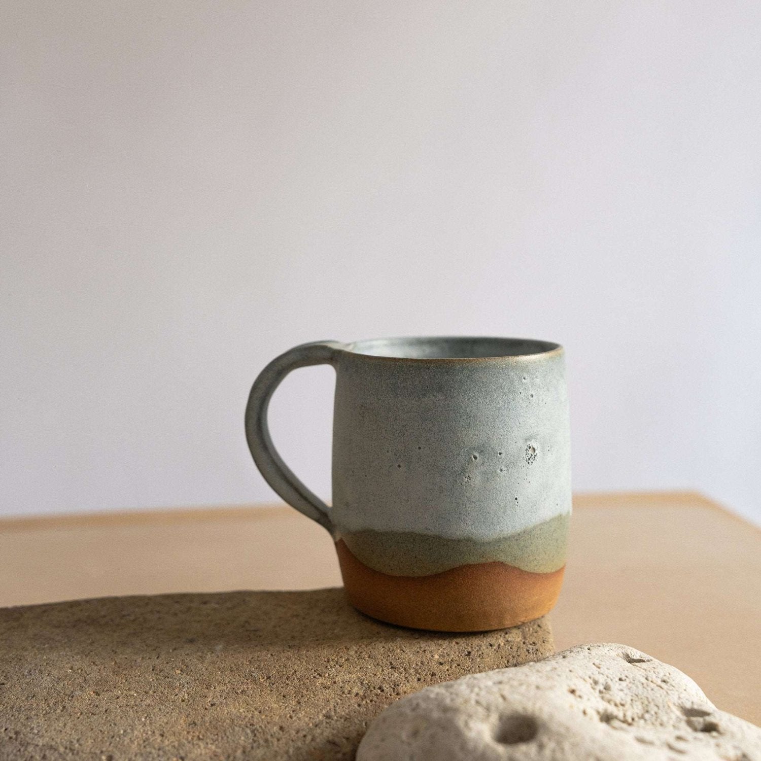 Handcrafted coffee mug with a cloudy blue glaze and an organic landscape-inspired design.