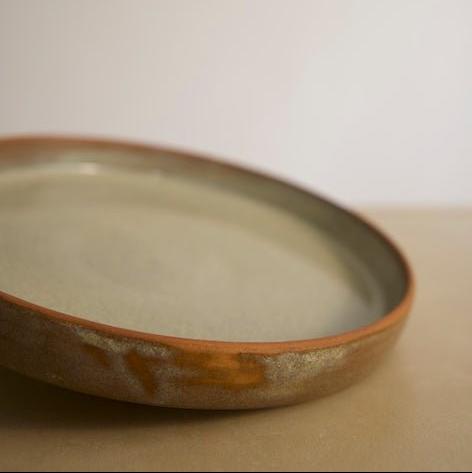 Artisanal green speckled meal plate styled with a rustic dining setup.