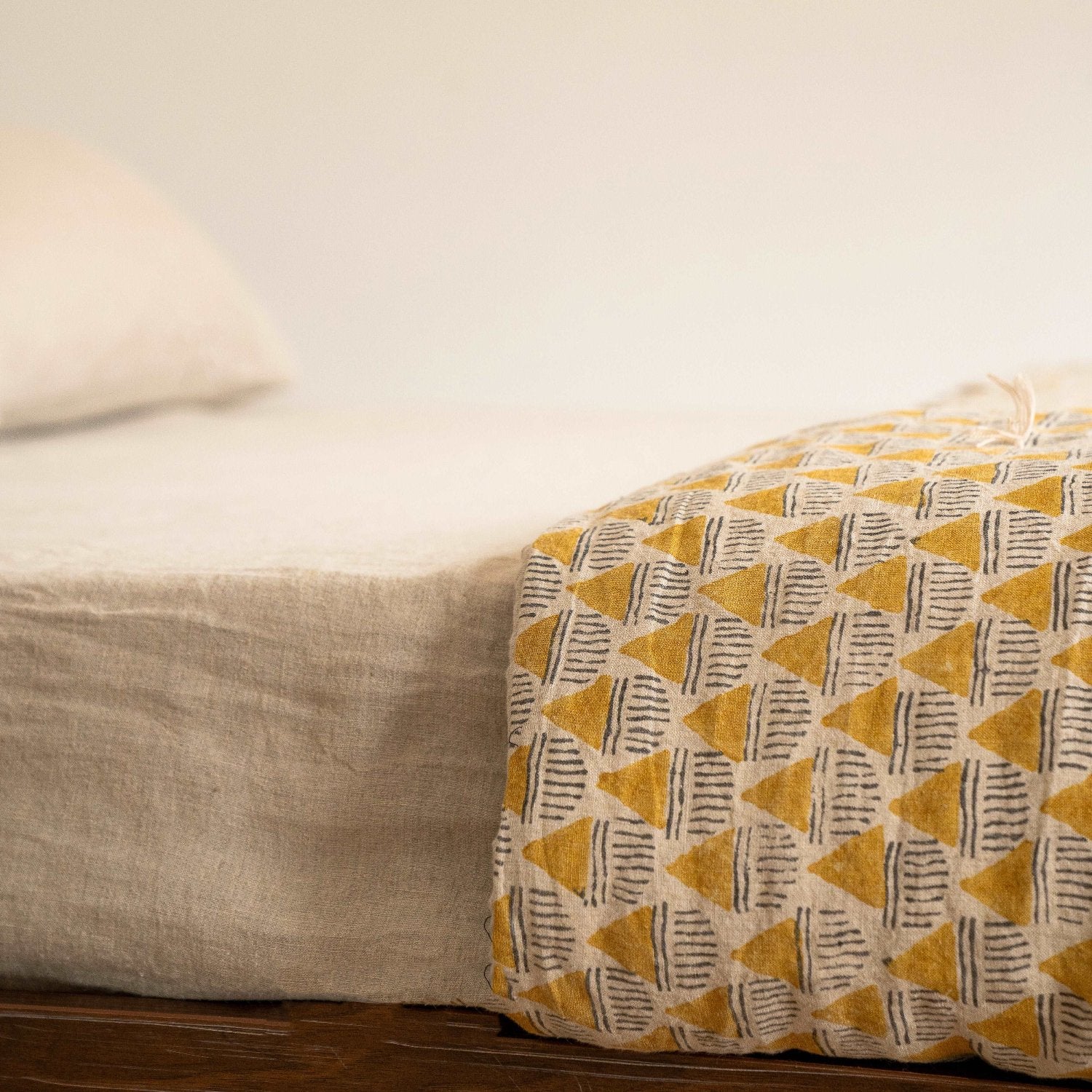 Subtle beige sheet draped over a neatly made bed.