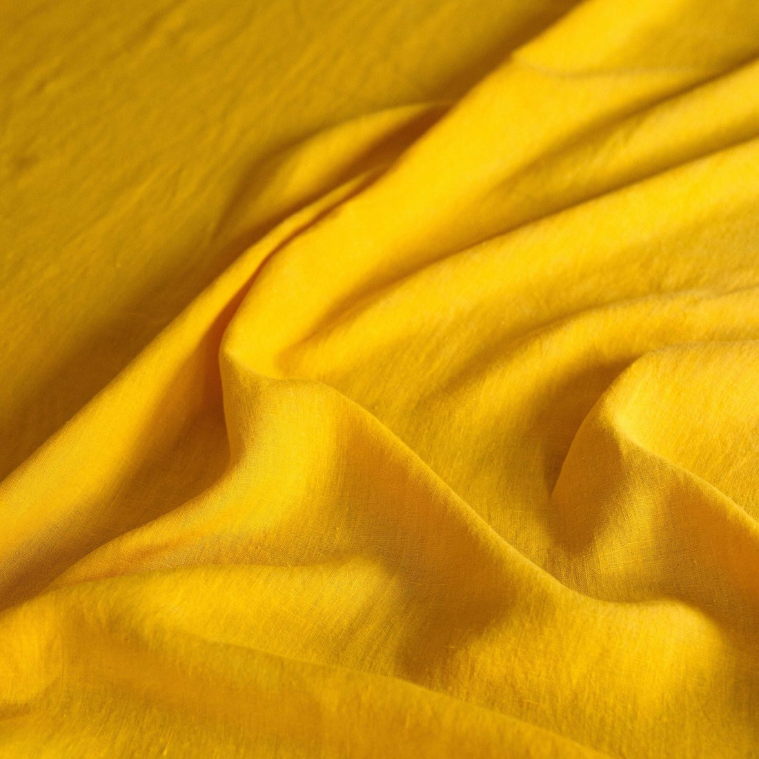 Close-up of yellow linen sheet showing breathable texture.