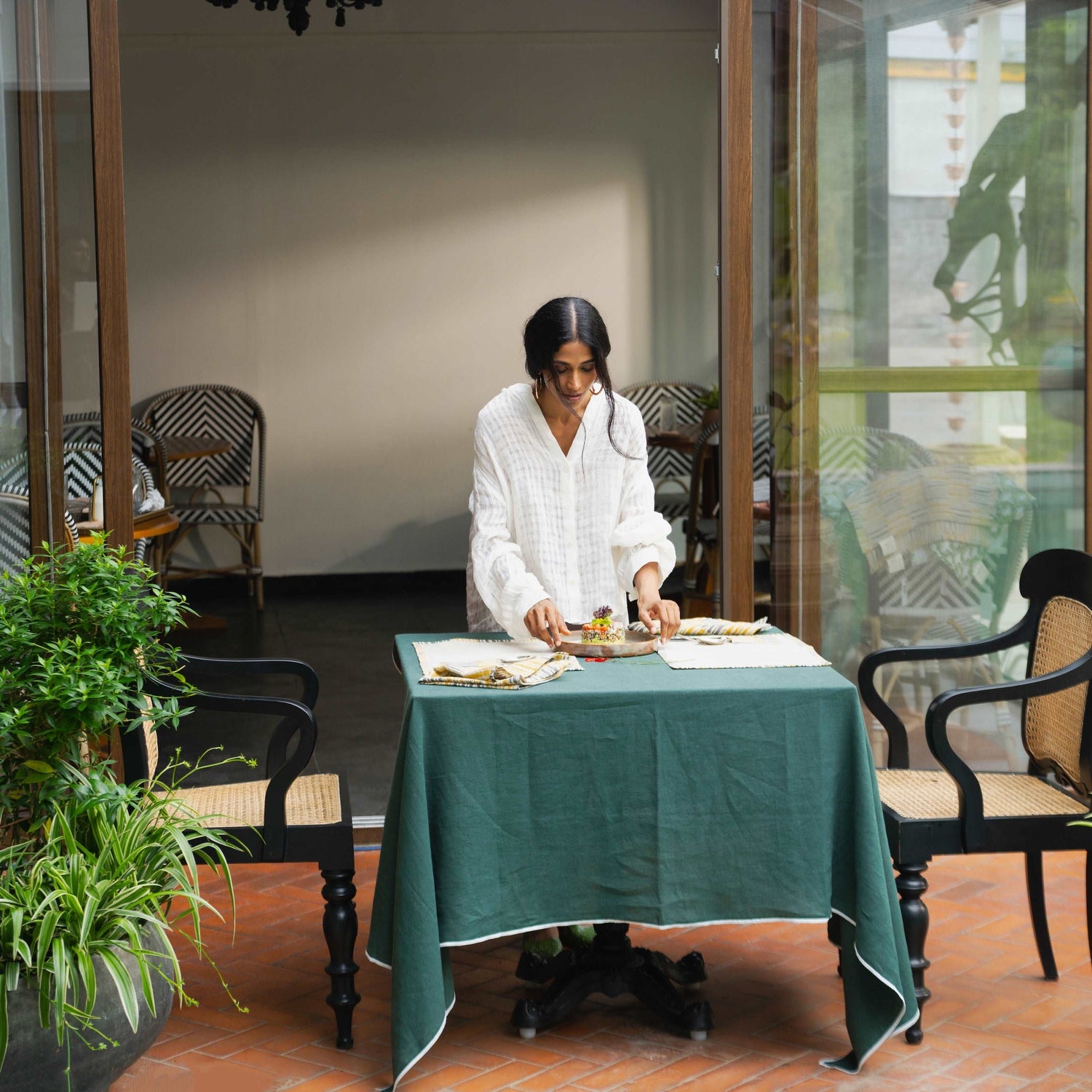 Woman setting the table with Ochrewood napkin, creating a warm dining ambiance.