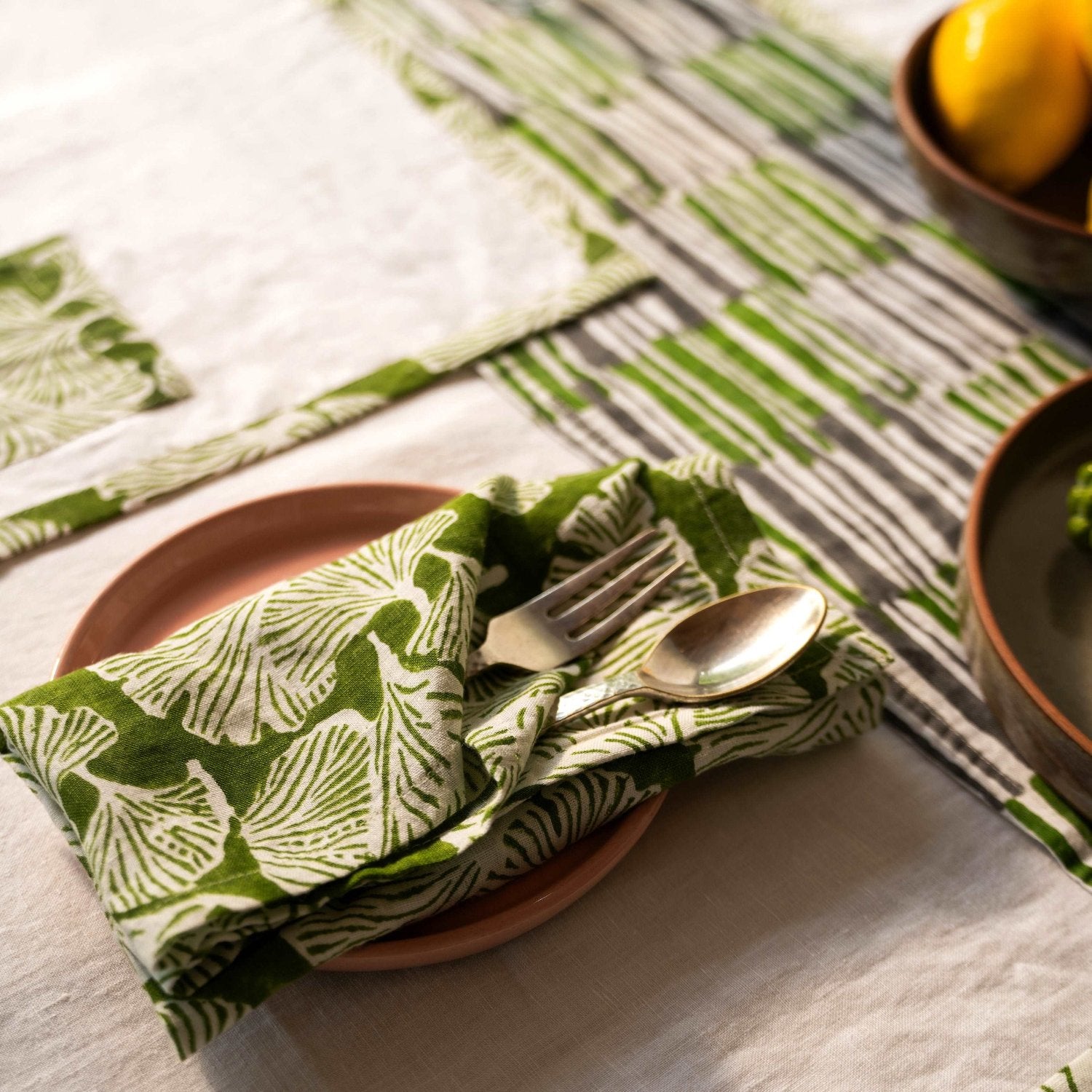 Dining table featuring a hand block printed linen runner in a deep kale hue.