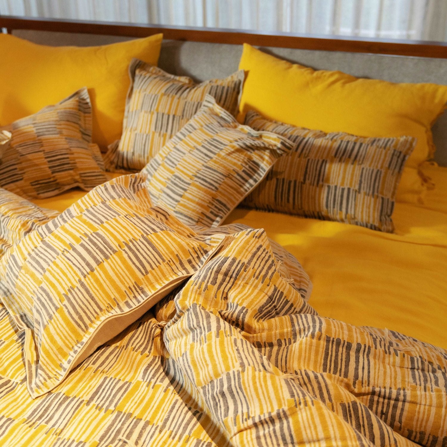 Golden yellow linen sheet paired with neutral throw pillows.