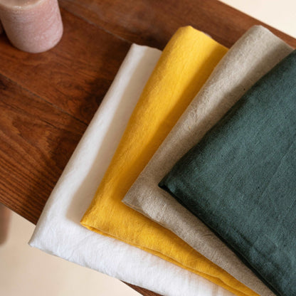 Olive linen tablecloth folded, emphasizing its smooth, durable fabric.