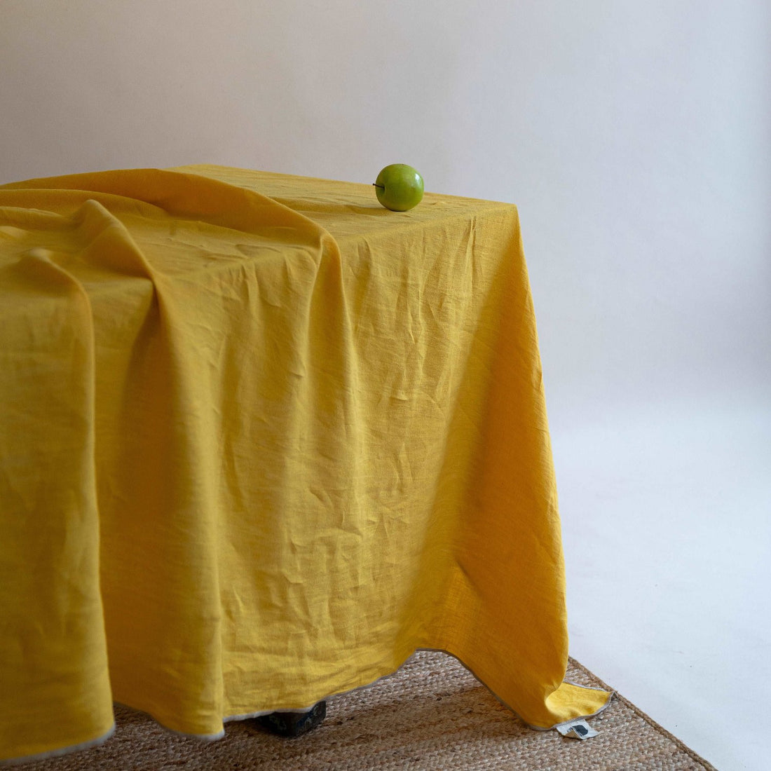 Dining table styled with summer yellow linen tablecloth and colorful tableware and a fruit as an object of art against the spendid background.