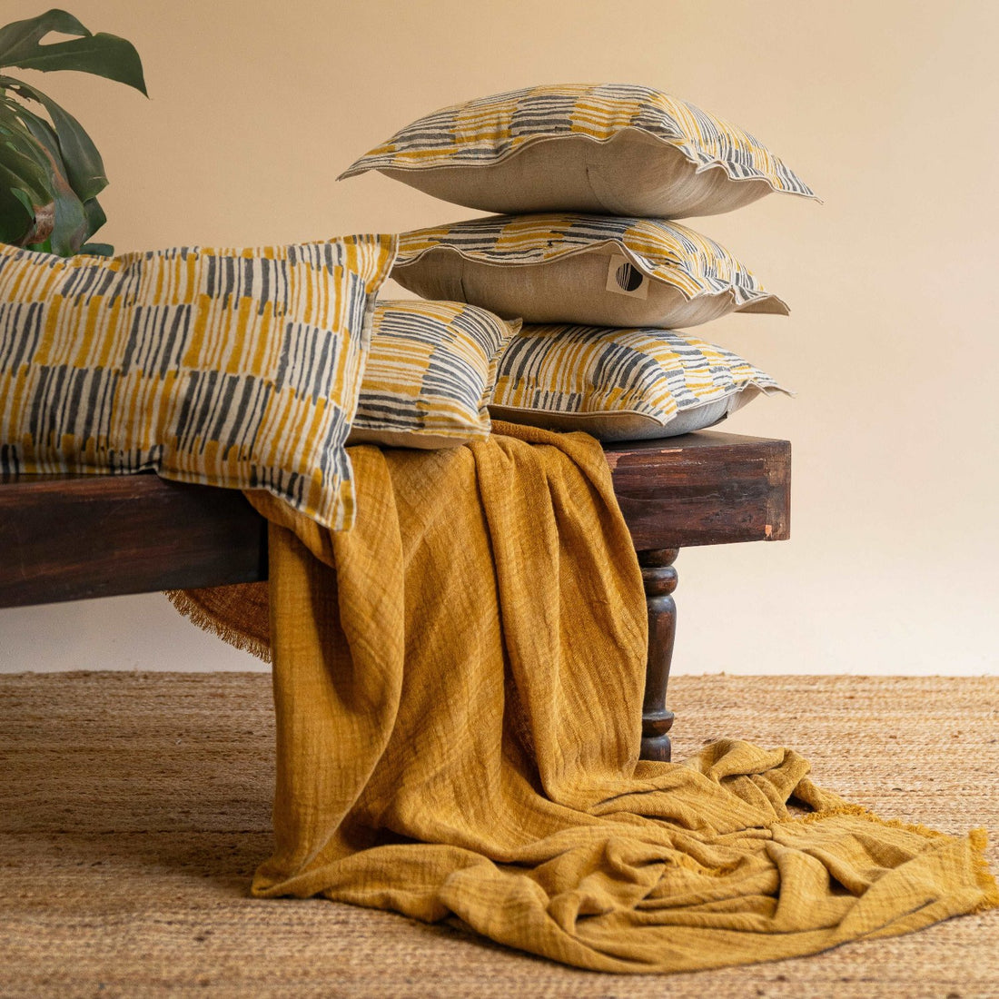 The Ochrewood cushion covers placed on a wooden bench, adding a warm accent to the living room décor along with the mustard ochre textured throw