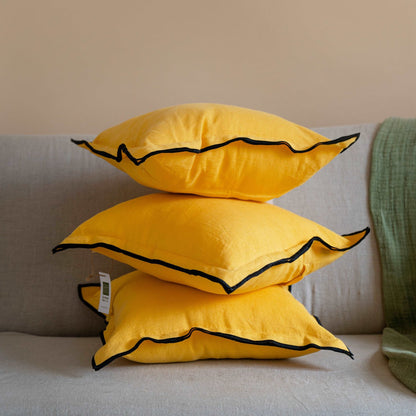 Stack of Summer Yellow linen cushion covers neatly folded, emphasizing the durability and craftsmanship of the fabric.