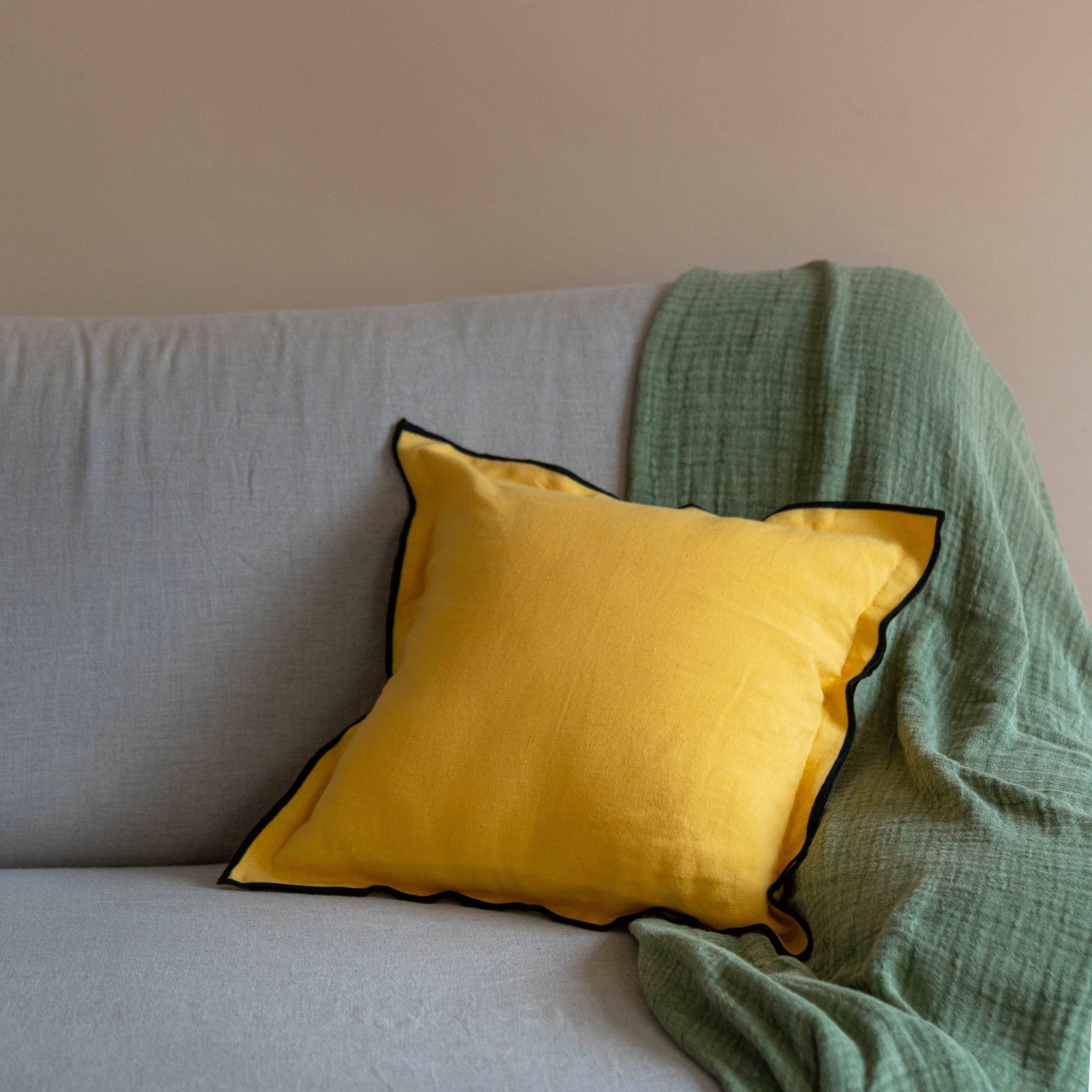 Solid Linen Cushion Cover in Summer Yellow paired with the sage green throw blanket by terra is a perfect marriage for any living room aesthetic adding a touch of luxury to the room.