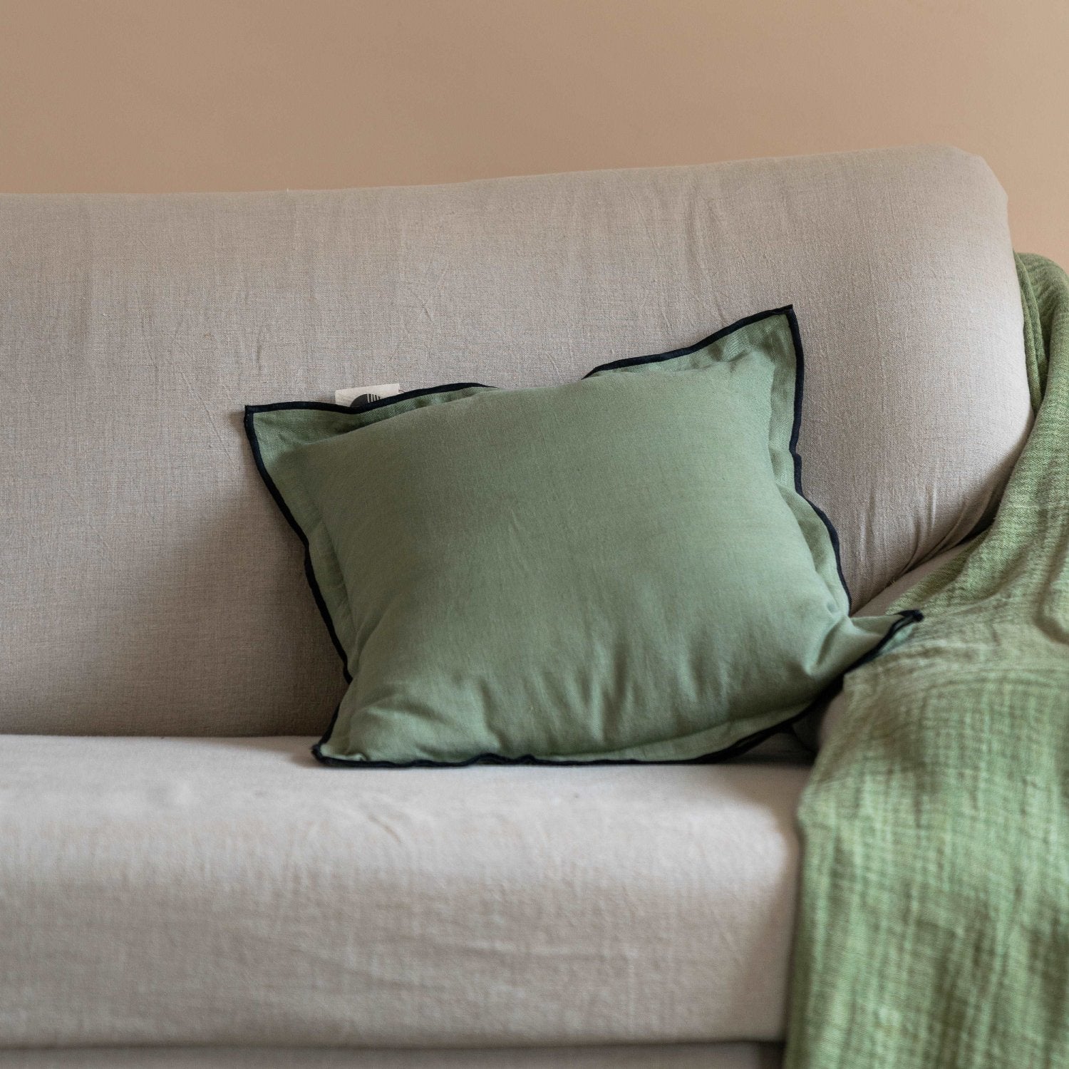 Olive green cushion cover placed on a beige sofa, complementing neutral-toned décor.